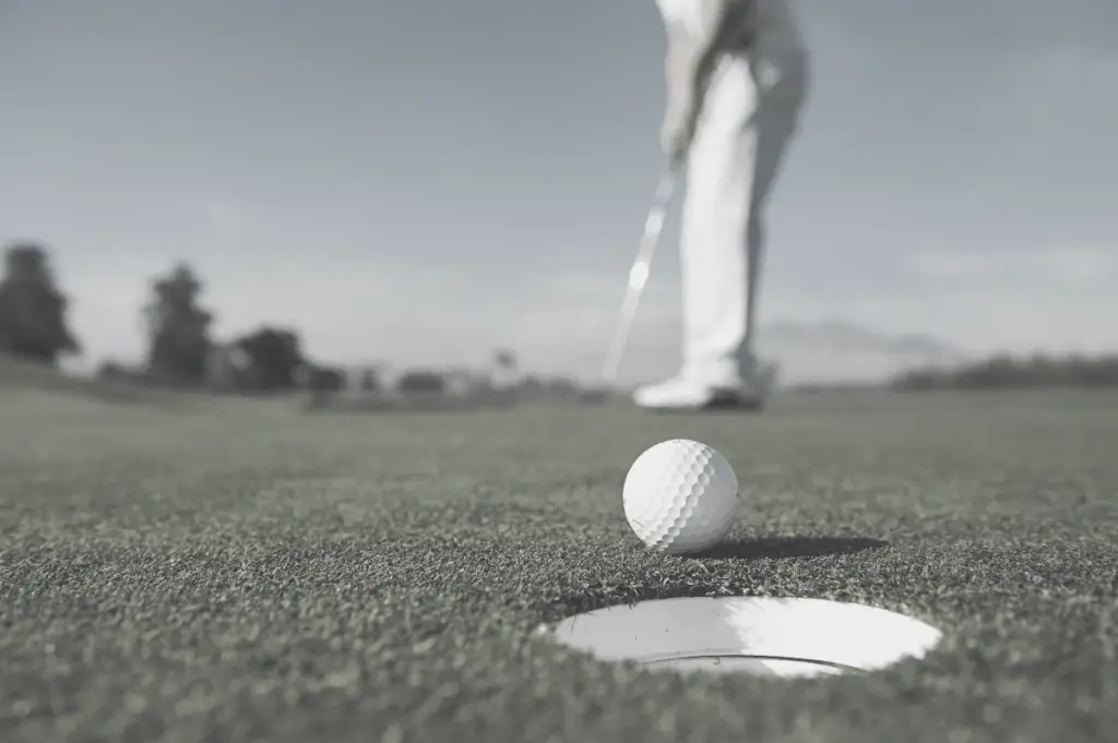 Man putting ball into hole 