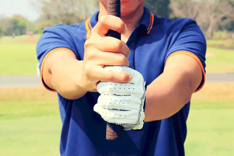 Golfer holding golf club with vardon grip 