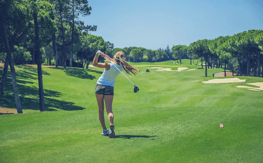 Woman swinging golf club