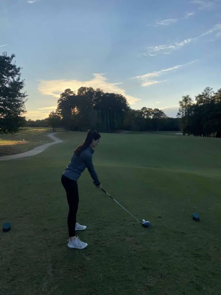 Woman golfer testing out the Callaway Solaire driver on the tee box of a golf course 